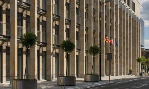 Gmach urzędu z flagami, przed budynkiem drzewka